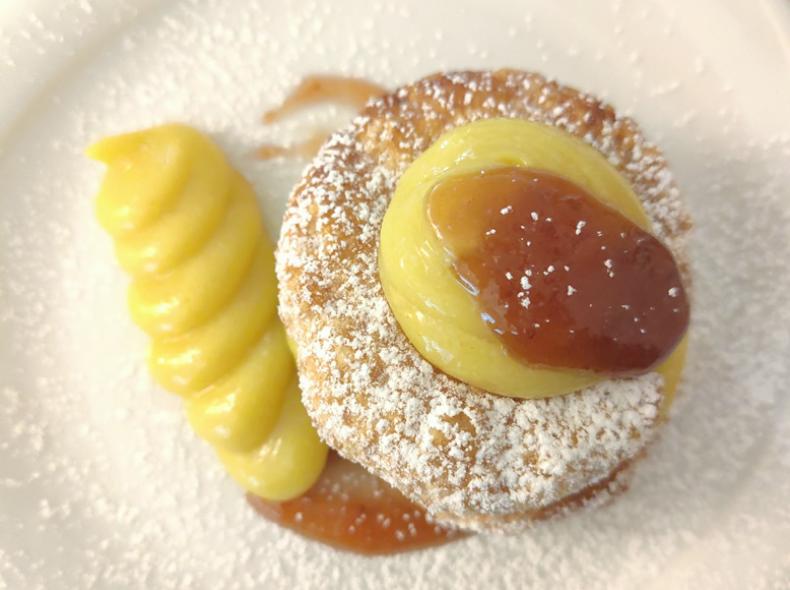 Crostata con griglia di pasta frolla e ripieno al cioccolato su piatto dorato.