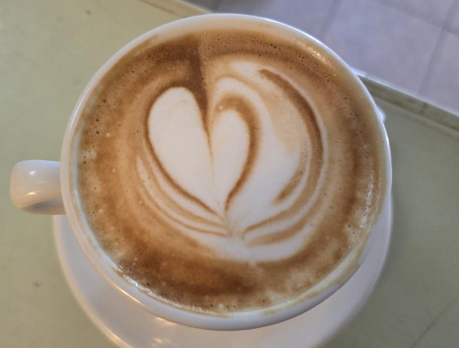 Cappuccino con latte art a forma di cuore in una tazza bianca.