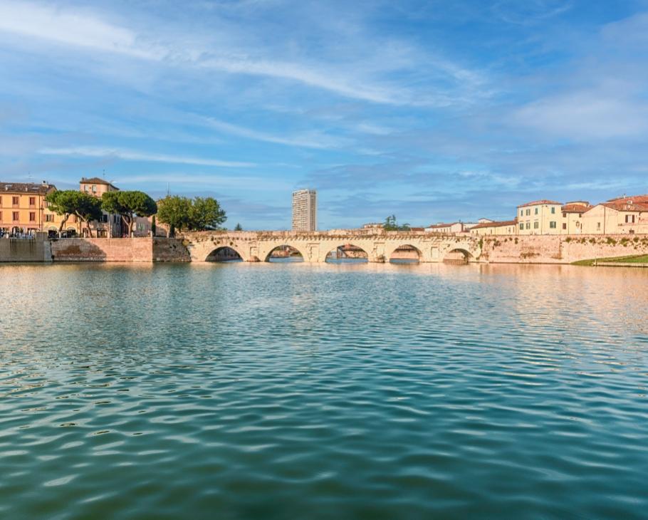 Ponte storico su un fiume con edifici e cielo sereno.