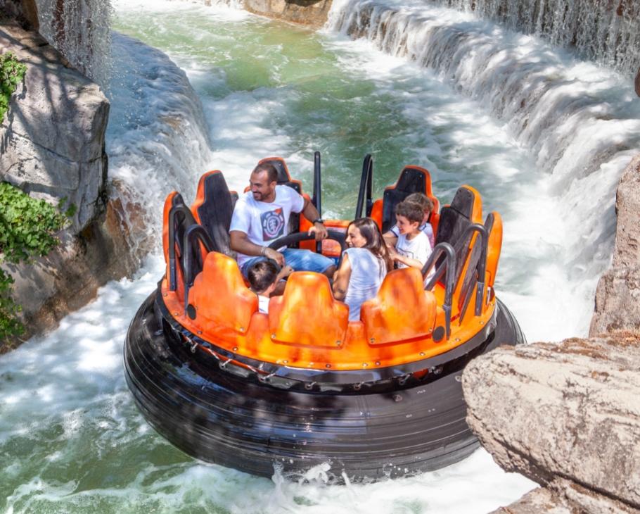 Famiglia su giostra d'acqua in un parco divertimenti, circondata da rapide e cascate.